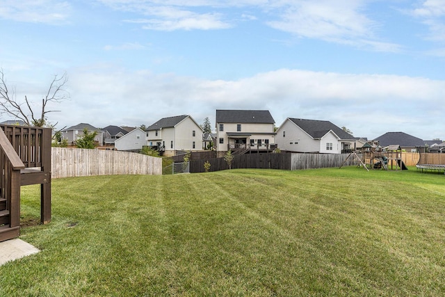 view of yard with a trampoline, a fenced backyard, and a residential view