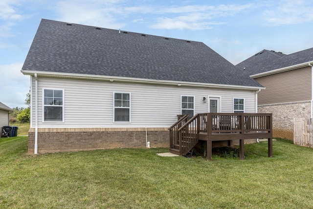 rear view of property featuring a deck, a yard, and roof with shingles