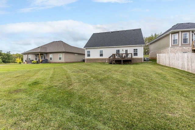 rear view of property featuring cooling unit, a lawn, a wooden deck, and fence