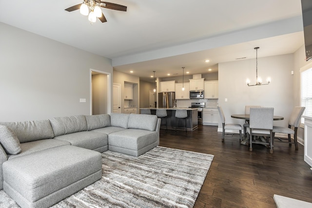 living area featuring recessed lighting, dark wood finished floors, and ceiling fan with notable chandelier