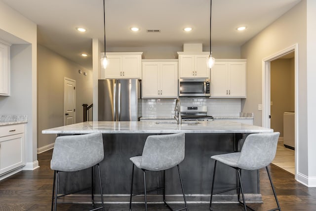 kitchen featuring stainless steel appliances, a sink, visible vents, white cabinets, and dark wood finished floors