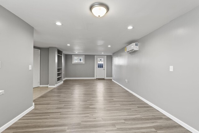 below grade area with recessed lighting, baseboards, wood finished floors, and a wall mounted air conditioner