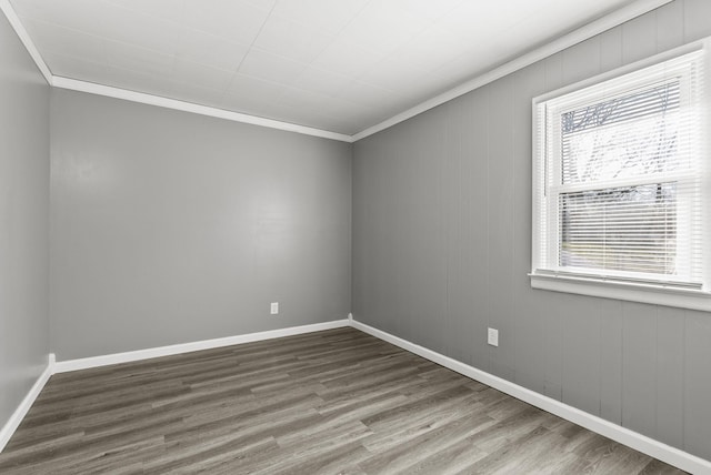 spare room with ornamental molding, baseboards, and wood finished floors