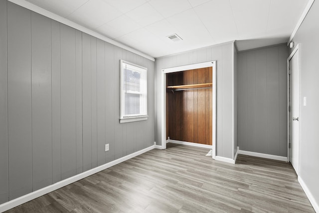 unfurnished bedroom with a closet, wood finished floors, visible vents, and baseboards