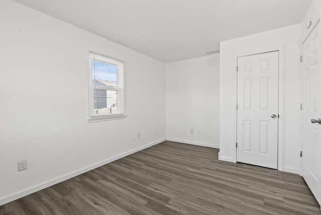 unfurnished bedroom featuring dark wood finished floors, visible vents, and baseboards