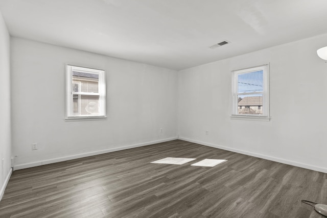 spare room featuring baseboards, visible vents, and dark wood-style flooring