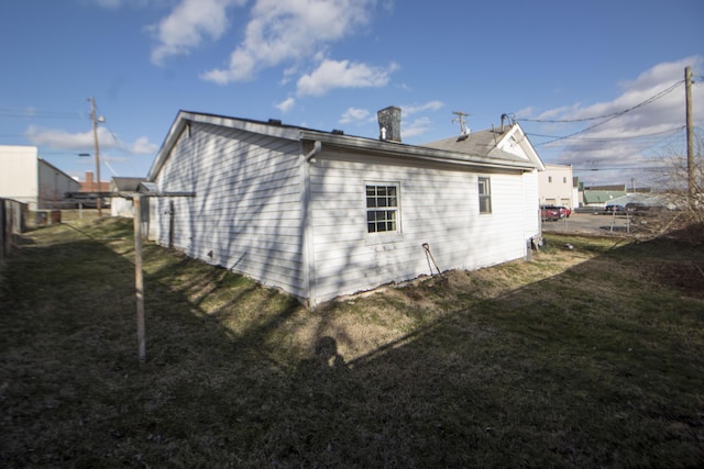 view of home's exterior with a lawn and fence