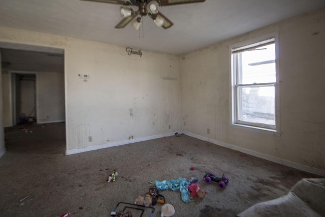 carpeted spare room with a ceiling fan and baseboards