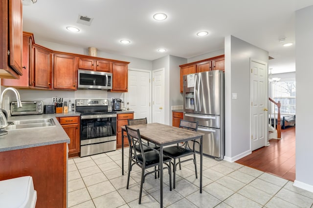 kitchen featuring stainless steel appliances, light tile patterned flooring, a sink, and visible vents