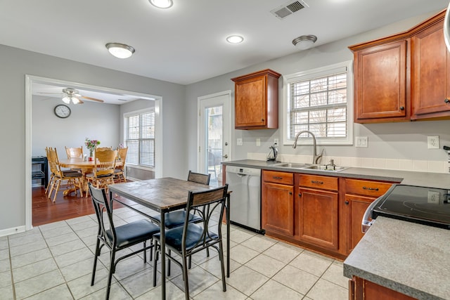 kitchen with brown cabinets, visible vents, appliances with stainless steel finishes, light tile patterned flooring, and a sink