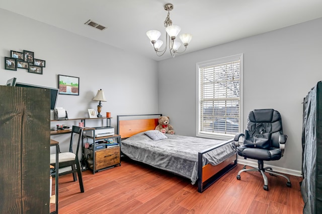 bedroom featuring light wood finished floors, baseboards, visible vents, and a chandelier