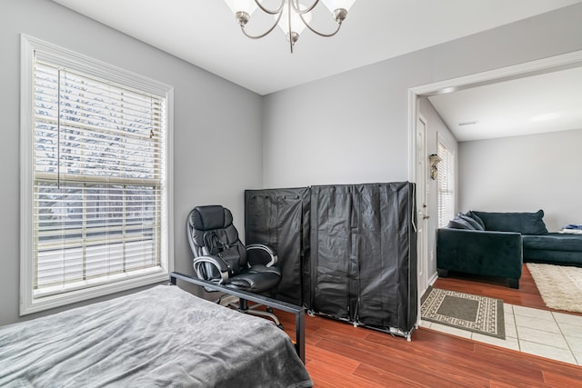 bedroom with multiple windows, a chandelier, and wood finished floors