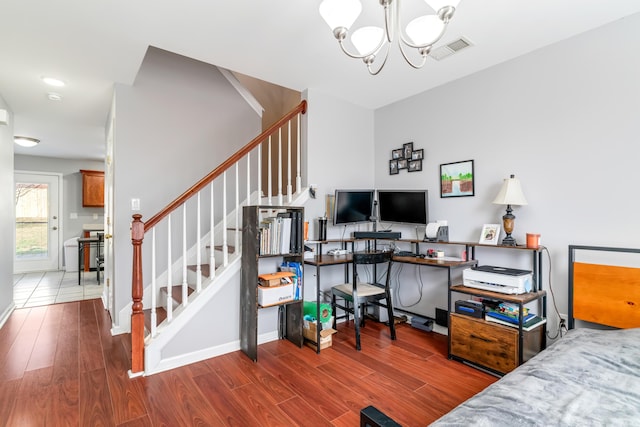 bedroom featuring wood finished floors, visible vents, and a notable chandelier