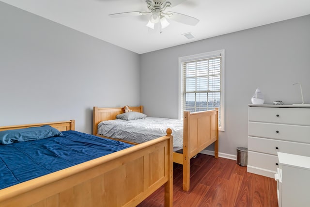 bedroom with dark wood-style floors, visible vents, baseboards, and a ceiling fan