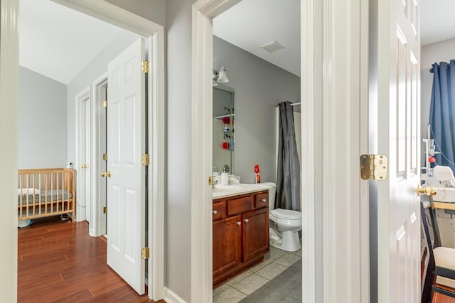 bathroom featuring toilet, visible vents, wood finished floors, and vanity