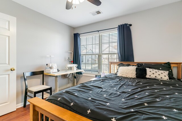 bedroom with ceiling fan, lofted ceiling, wood finished floors, visible vents, and baseboards