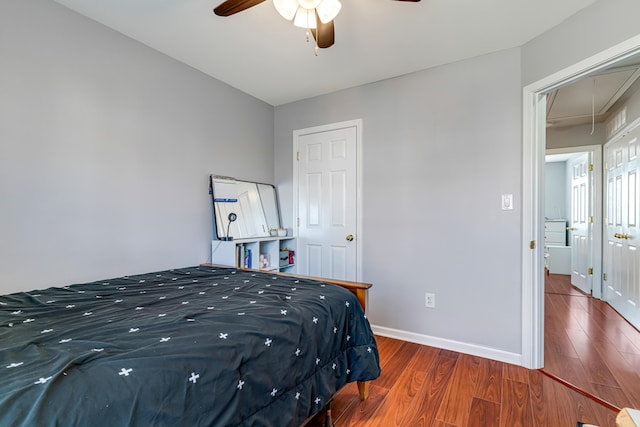 bedroom with attic access, a ceiling fan, baseboards, and wood finished floors