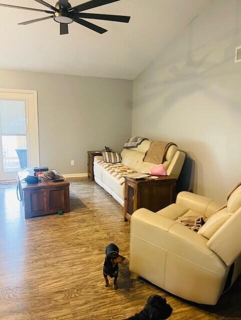 bedroom featuring a ceiling fan, vaulted ceiling, baseboards, and wood finished floors