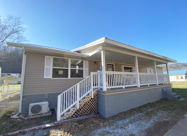 view of front facade featuring covered porch, metal roof, stairway, and ac unit