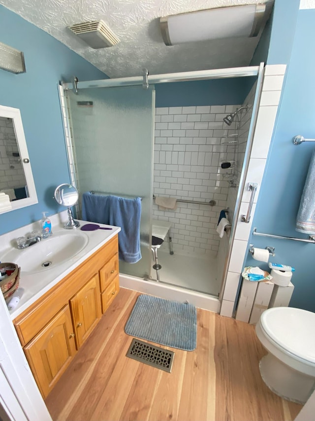 full bathroom with a stall shower, visible vents, and wood finished floors