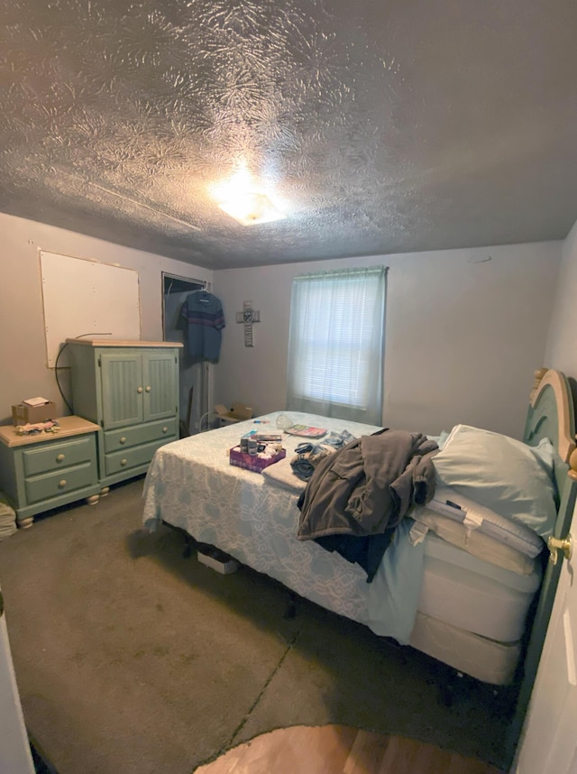 bedroom with a textured ceiling and dark carpet