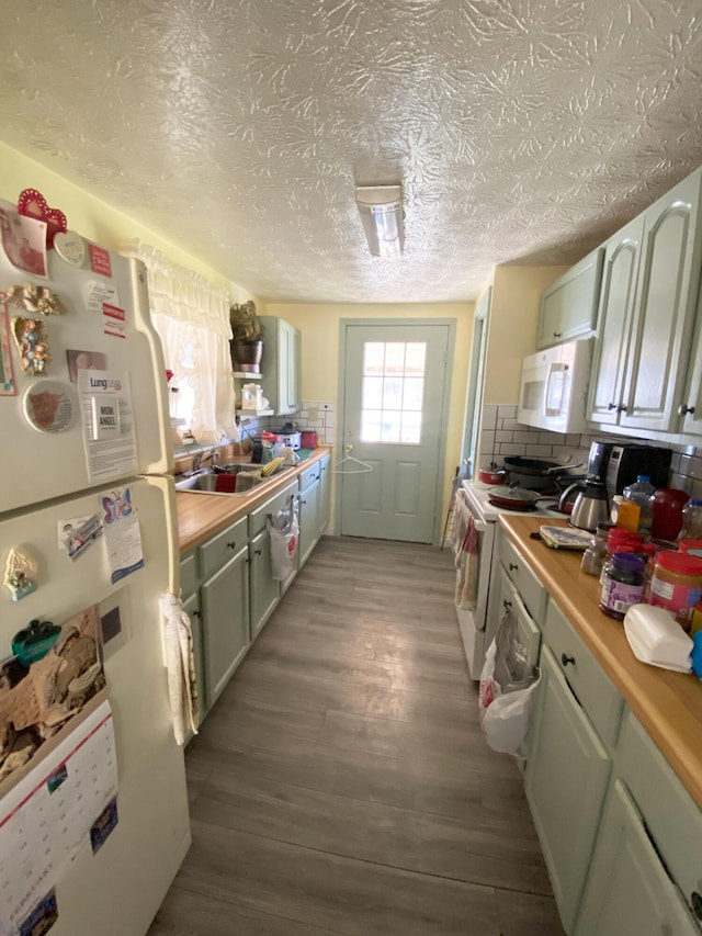 kitchen featuring white appliances, decorative backsplash, a textured ceiling, light wood-type flooring, and a sink