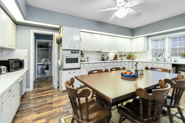 kitchen with white cabinets, light countertops, dark wood-type flooring, and white oven