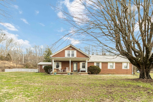 view of front of house with brick siding, a front lawn, a porch, and fence