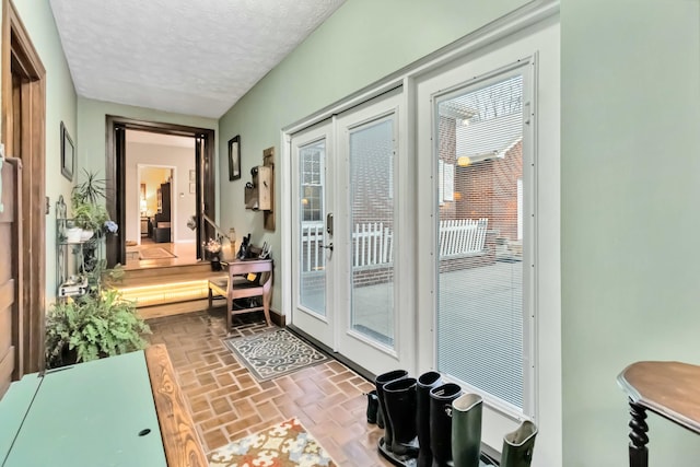 entryway with brick floor, french doors, and a textured ceiling