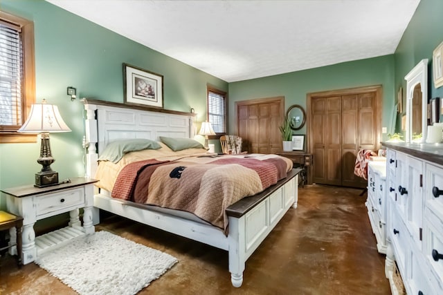 bedroom with finished concrete flooring and two closets