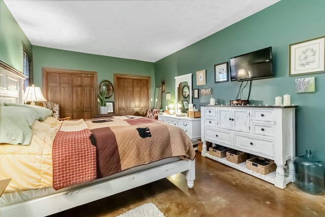 bedroom featuring concrete floors and two closets