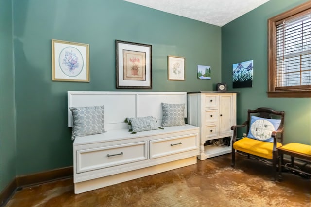 living area with a textured ceiling, baseboards, and concrete flooring