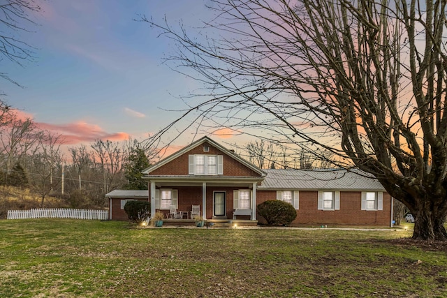 bungalow-style home featuring a yard, fence, a porch, and brick siding