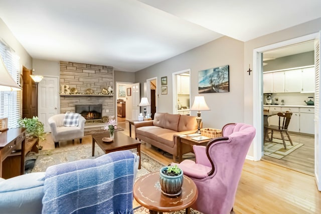 living area featuring a stone fireplace and light wood-style flooring