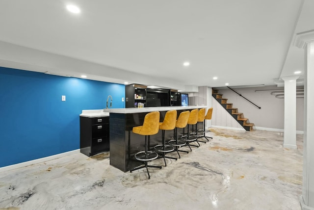 bar with baseboards, concrete floors, stairway, and indoor wet bar