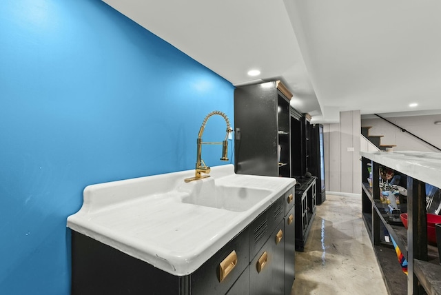 kitchen featuring light countertops, dark cabinets, recessed lighting, and finished concrete floors