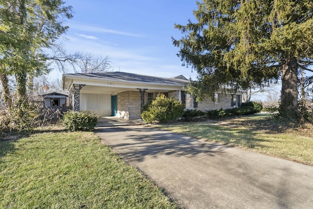 view of front of house with concrete driveway, a carport, stone siding, and a front yard