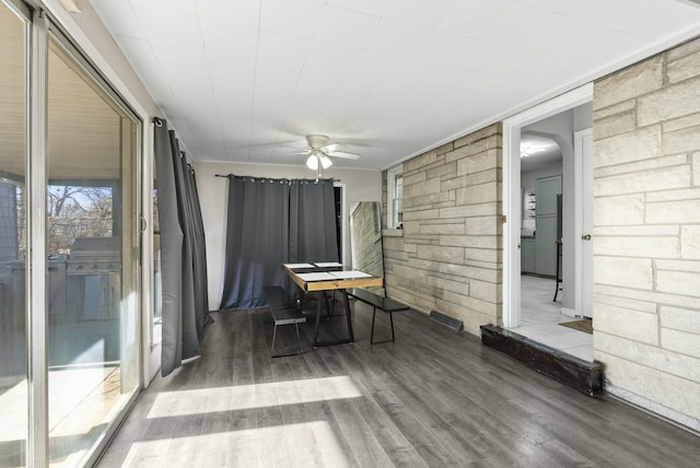 unfurnished sunroom featuring a ceiling fan and arched walkways