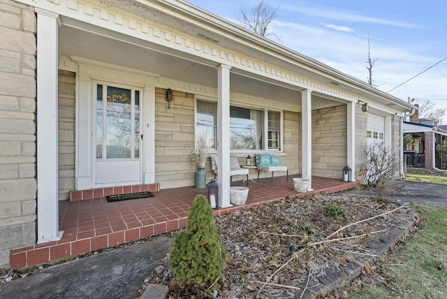 property entrance featuring an attached garage, covered porch, and aphalt driveway