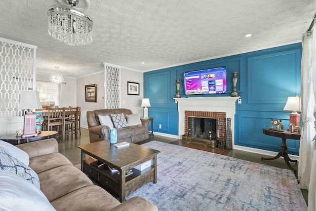 living room featuring an inviting chandelier, a fireplace, a decorative wall, and crown molding