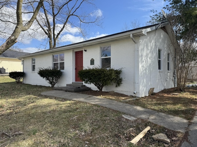 ranch-style home with entry steps, brick siding, and a front lawn