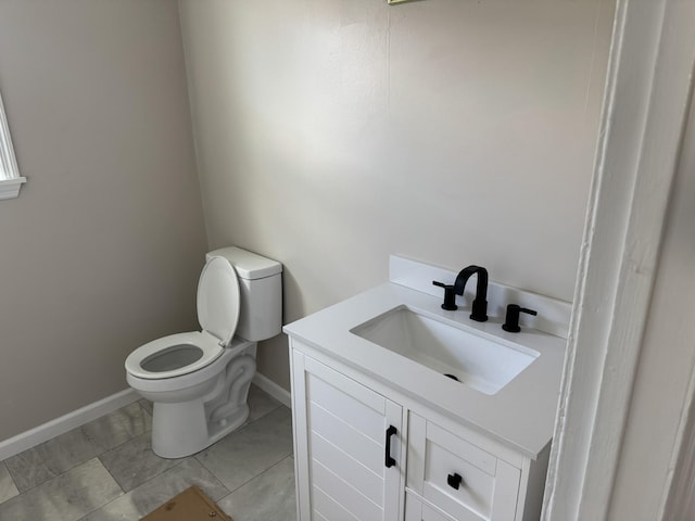 half bathroom featuring baseboards, vanity, and toilet