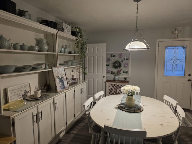 dining area featuring dark wood-style flooring and a textured ceiling