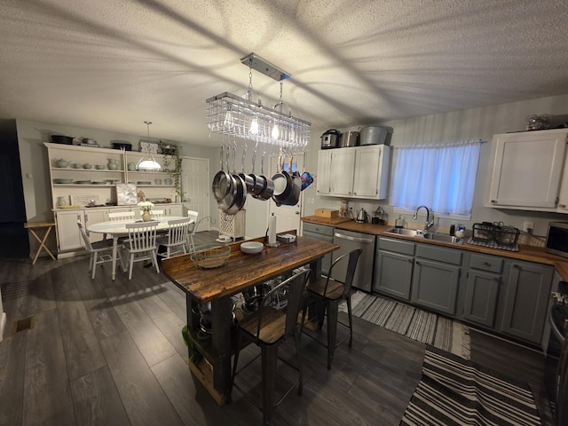 kitchen featuring a sink, stainless steel appliances, dark wood-type flooring, and wood counters