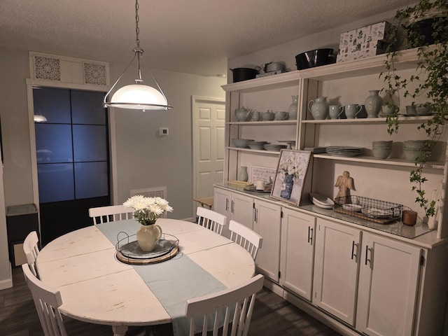 dining area with a textured ceiling and dark wood-type flooring