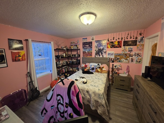 bedroom featuring a textured ceiling, baseboards, and wood finished floors