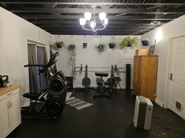 exercise room with a chandelier and baseboards