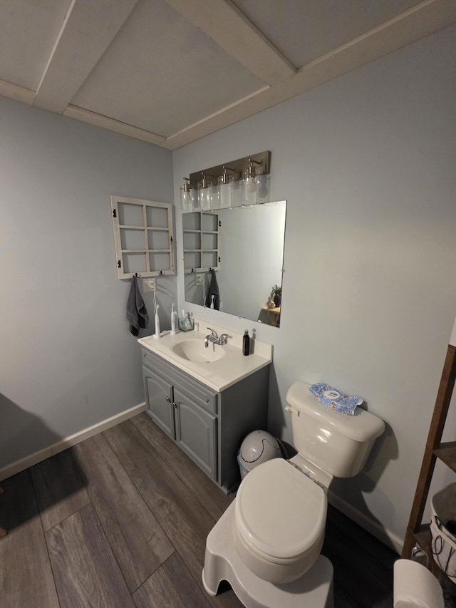 bathroom featuring baseboards, vanity, toilet, and wood finished floors