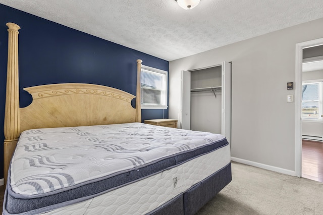 bedroom with baseboards, carpet flooring, baseboard heating, a closet, and a textured ceiling