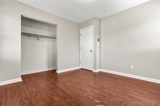 unfurnished bedroom featuring wood finished floors, baseboards, a closet, and a textured ceiling